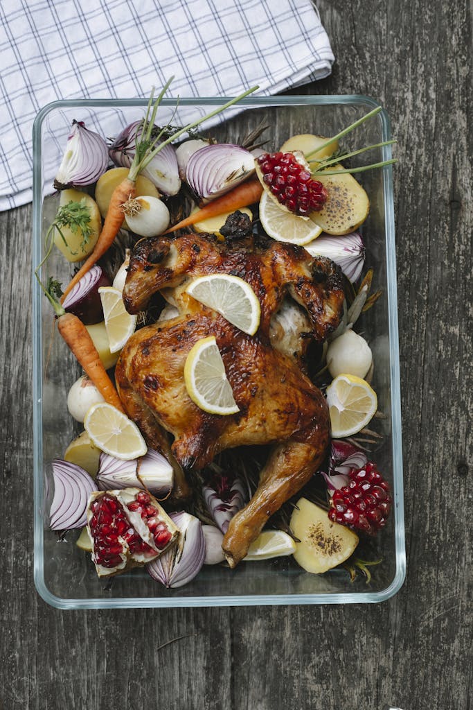 Tasty baked chicken with vegetable and fruit mix on table